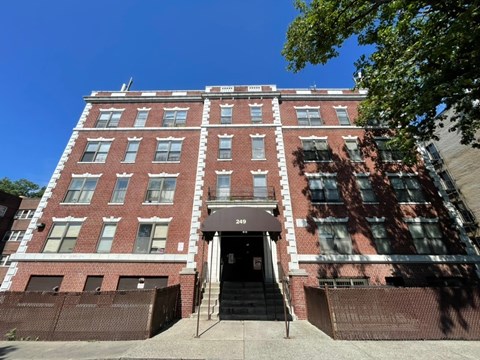 A red brick building with a black awning and a set of stairs leading up to the entrance.