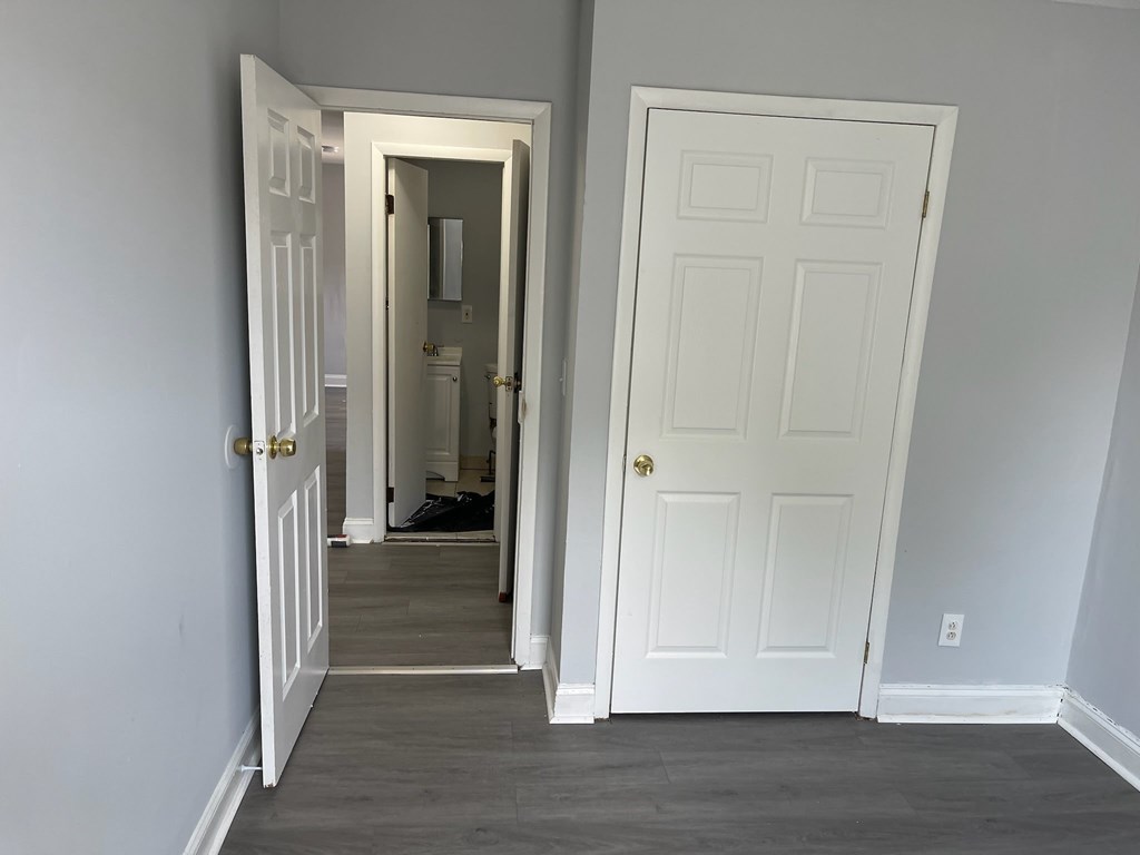 A hallway with two doors, one open, and a person standing in the doorway.