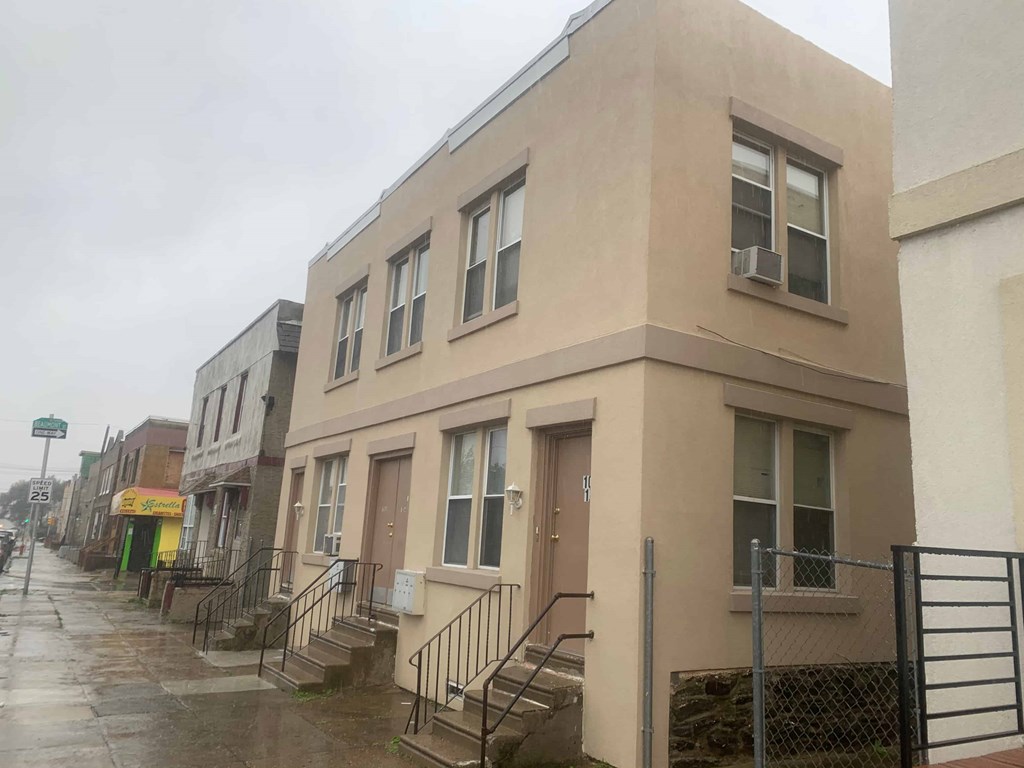 A beige building with a brown door and a window with a black frame.