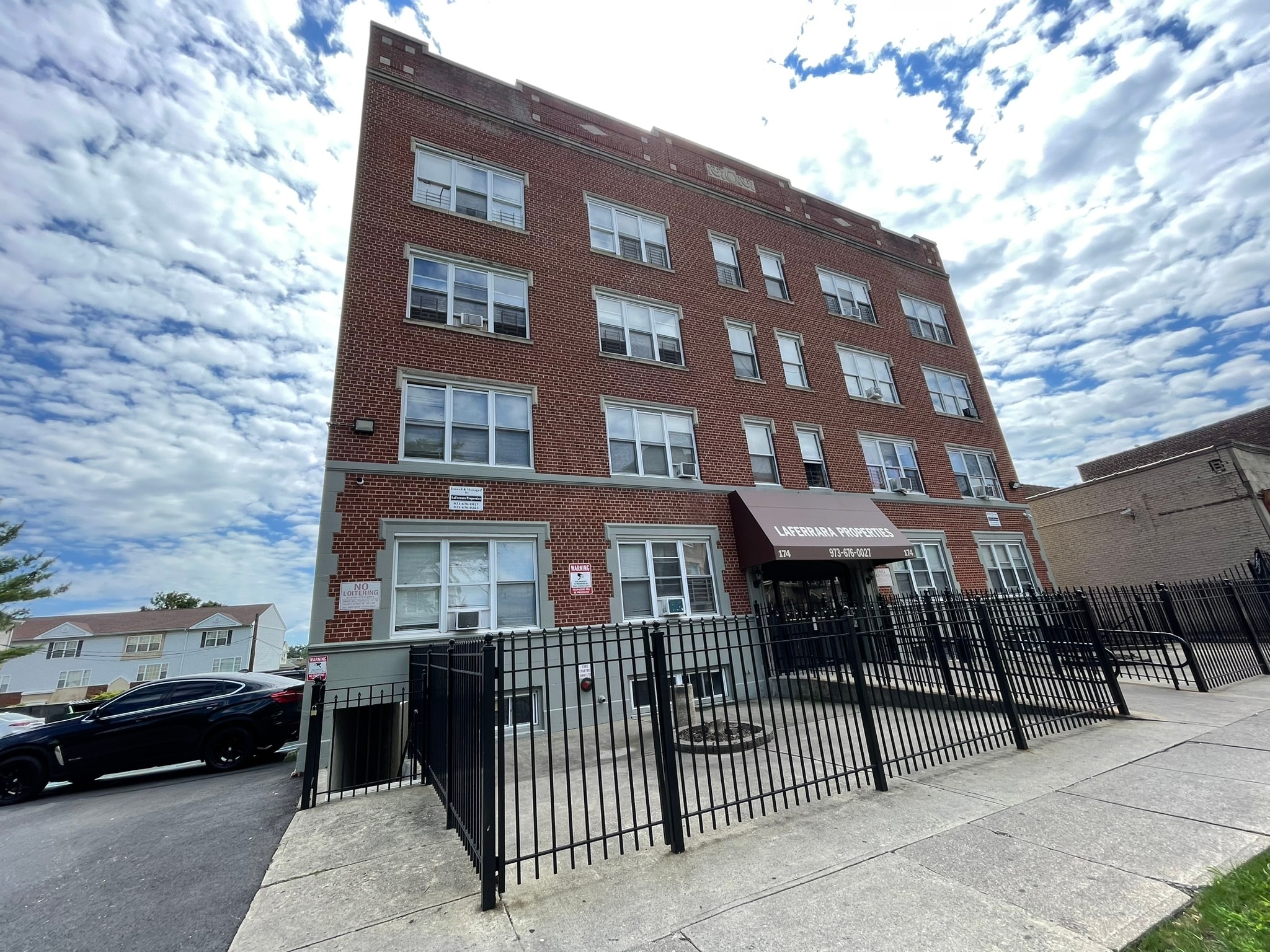 A red brick building with a black fence in front.