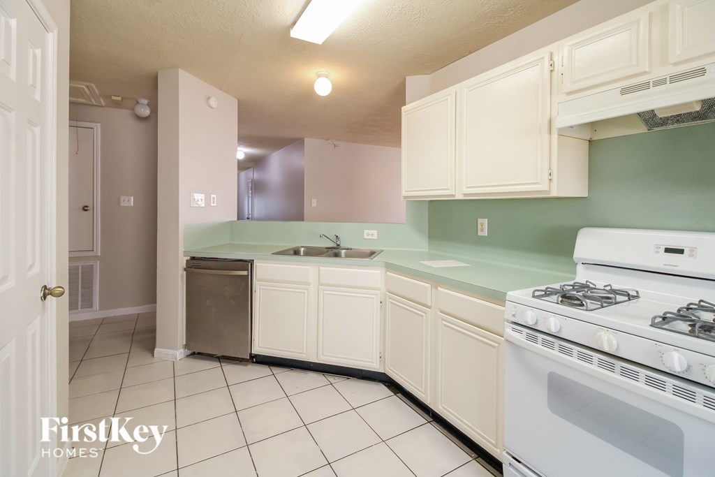 A kitchen with a stove, sink, and cabinets.