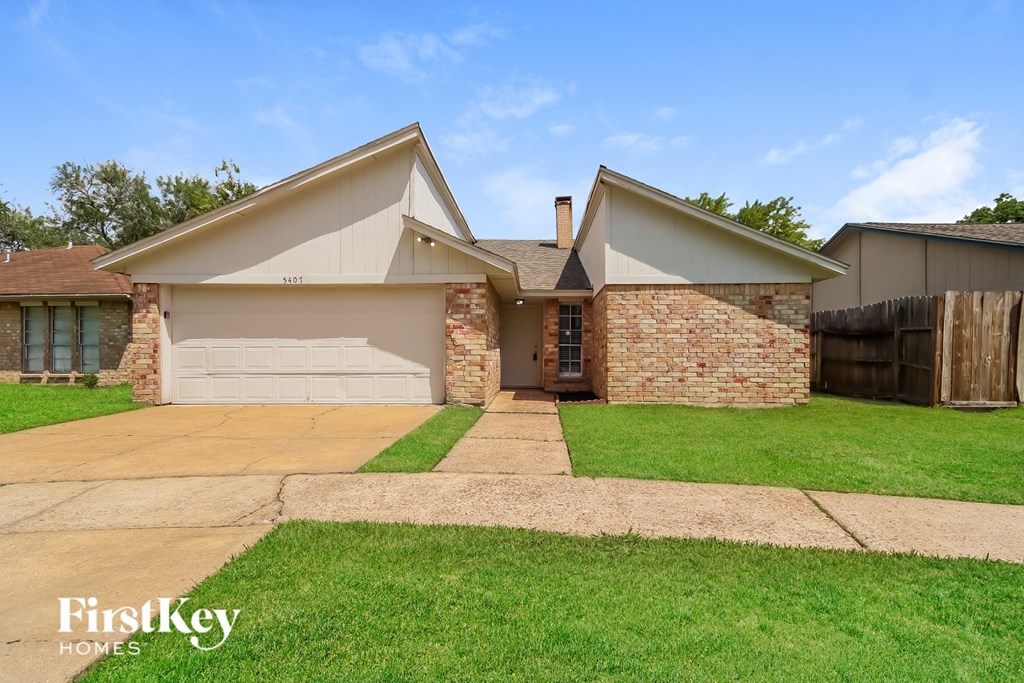 A house with a garage and a driveway in front of it.
