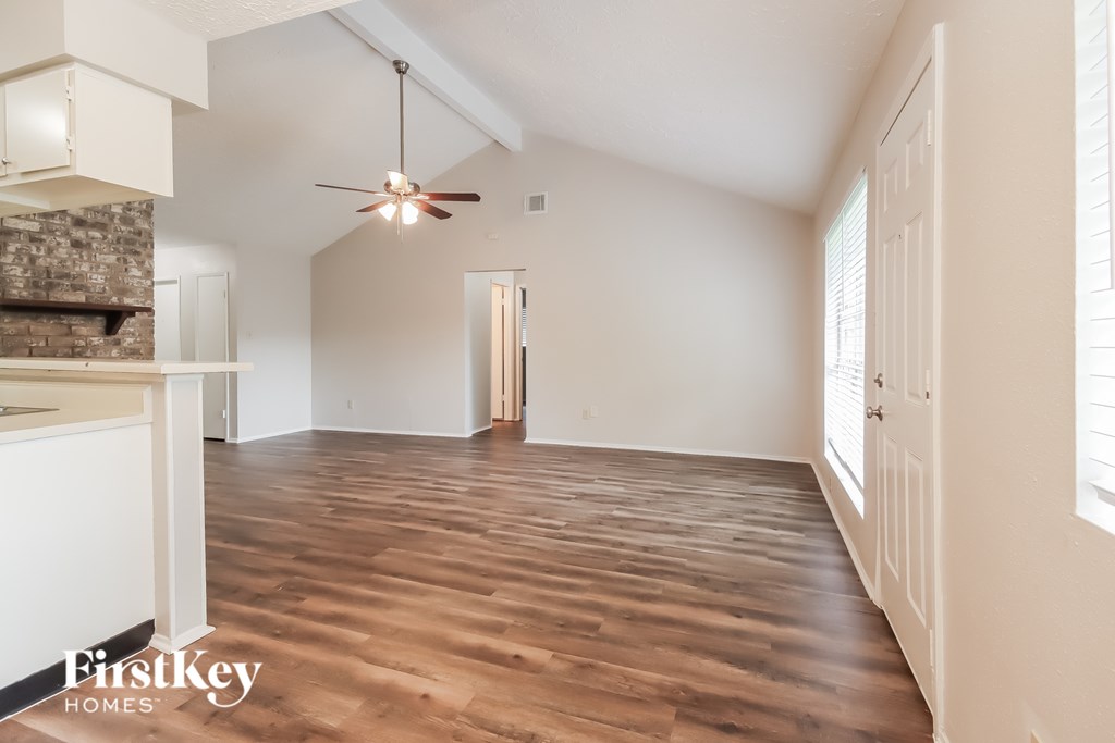 A spacious room with wooden flooring and a ceiling fan.