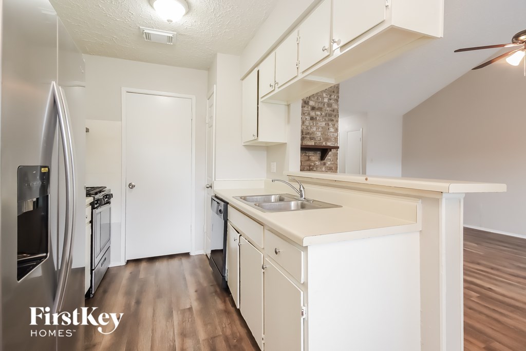 A kitchen with white cabinets and a stainless steel refrigerator.