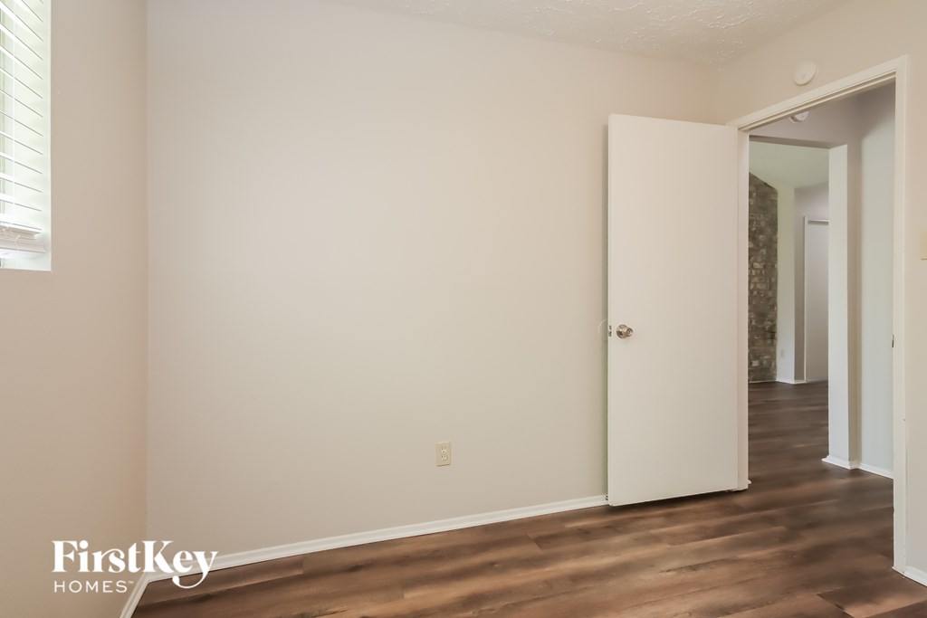 A room with a white door and wooden floor.
