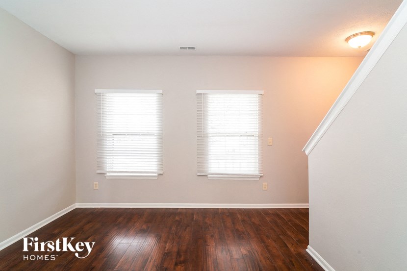 the living room of a home with wood floors and two windows