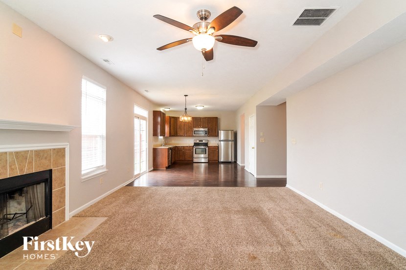 an empty living room with a fireplace and a ceiling fan