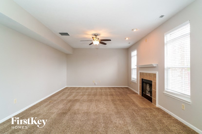 an empty living room with a fireplace and a ceiling fan