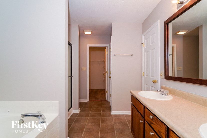 a bathroom with a sink and a mirror and a hall to a closet