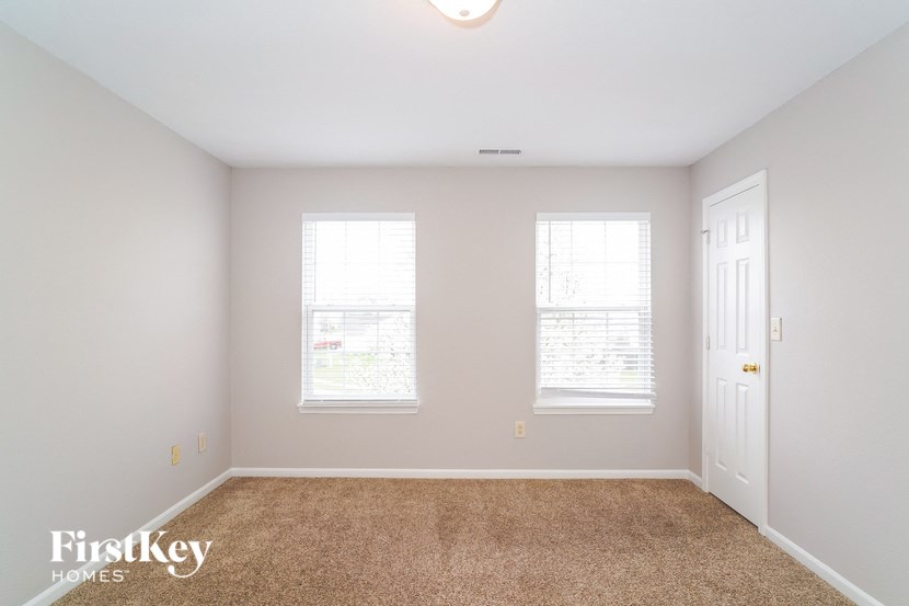a bedroom with a carpeted floor and three windows