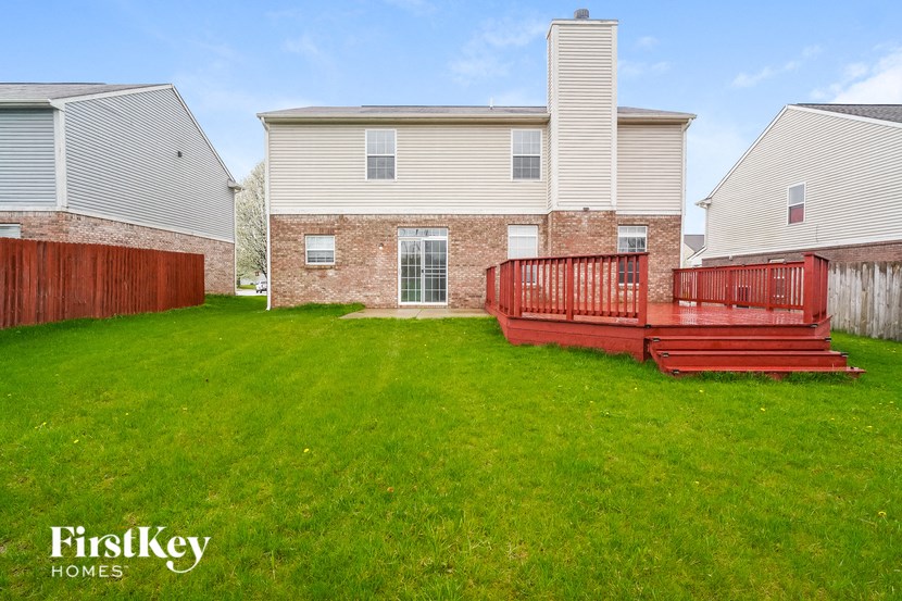 a backyard with a wooden deck in front of a house