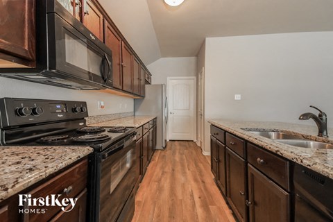 A kitchen with a black stove top oven and black microwave above it.