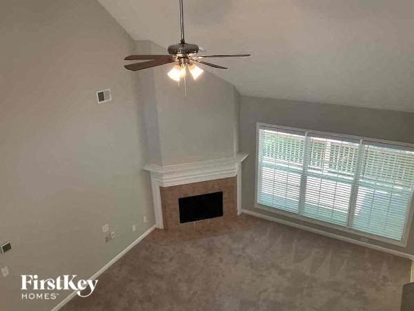 an empty living room with a ceiling fan and a window