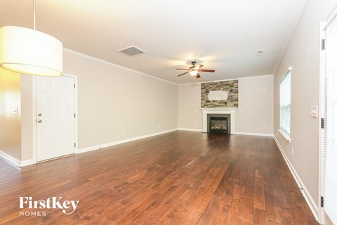 A spacious room with wooden floors and a fireplace.