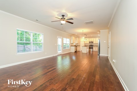 A spacious room with wooden floors and a ceiling fan.