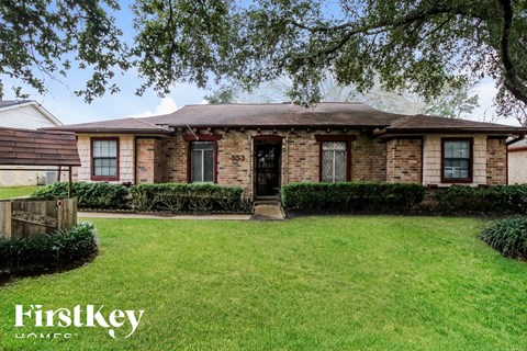 an old brick house with a lawn and a tree