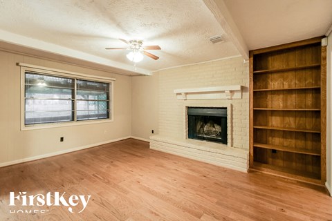 a living room with a brick fireplace and wooden shelves