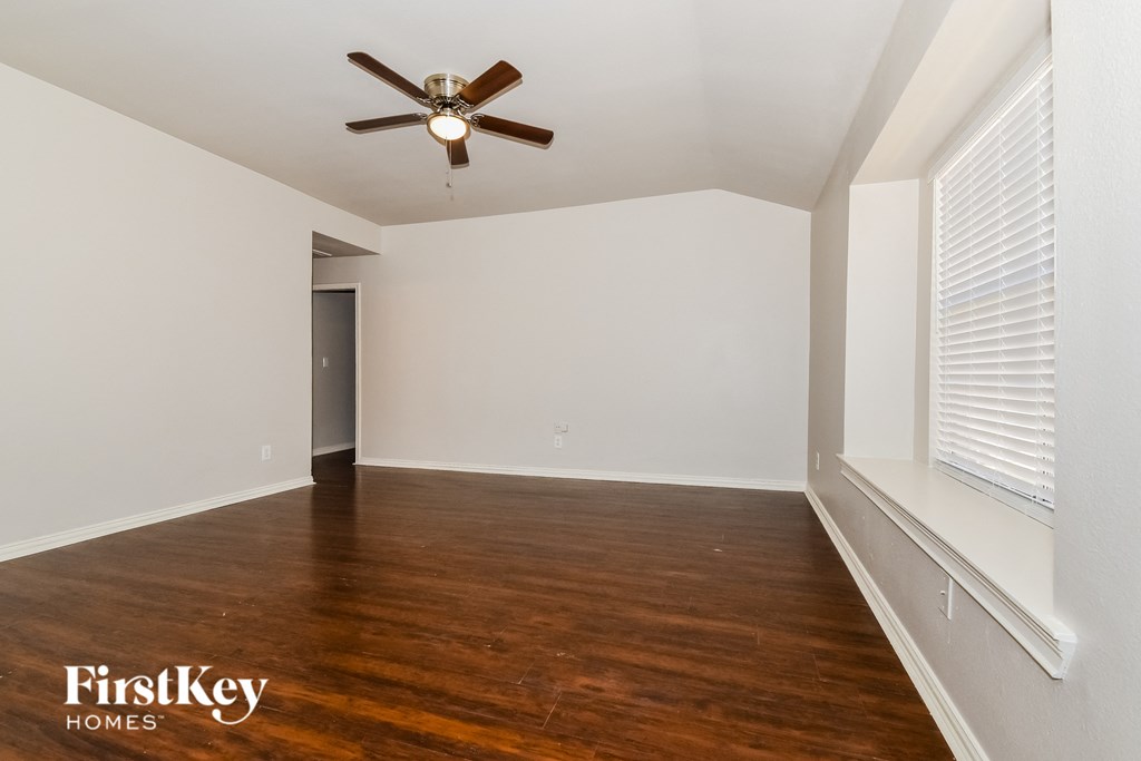 A room with a ceiling fan and wooden flooring.