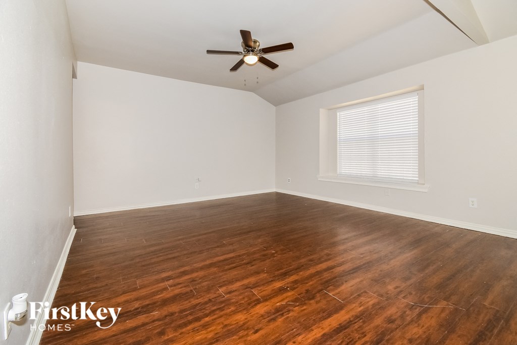 A room with wooden flooring and a ceiling fan.