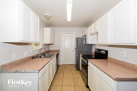 A kitchen with white cabinets and a marble countertop.