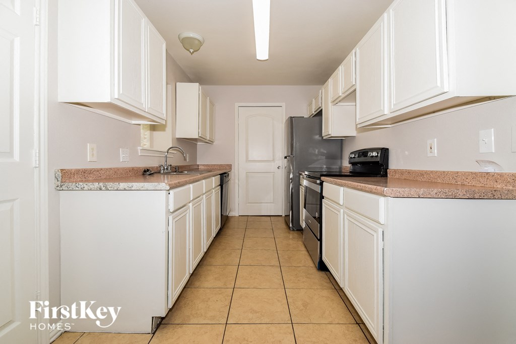 A kitchen with white cabinets and a granite countertop.
