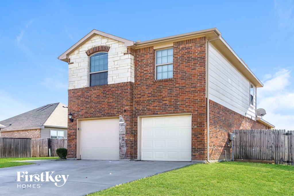 A brick house with a garage door and a satellite dish on the roof.