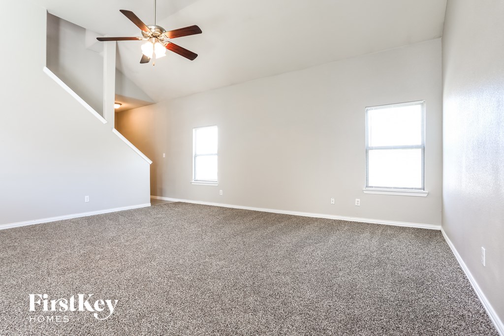 A spacious room with a carpeted floor and a ceiling fan.