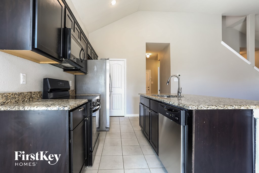 A kitchen with black cabinets and granite countertops.