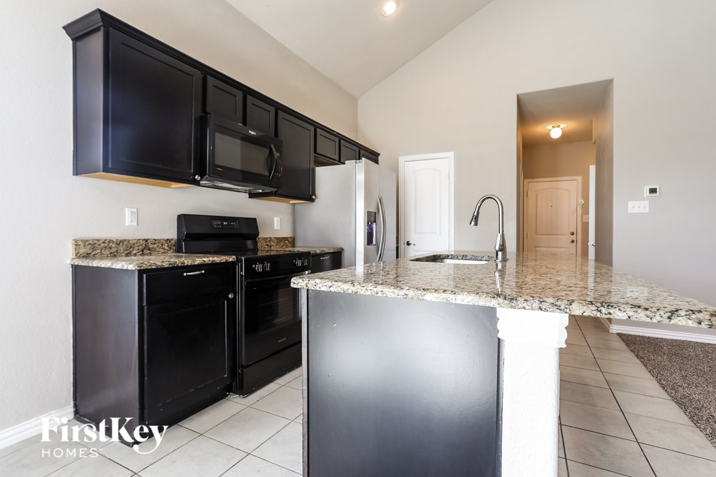 A kitchen with black cabinets and a granite countertop.