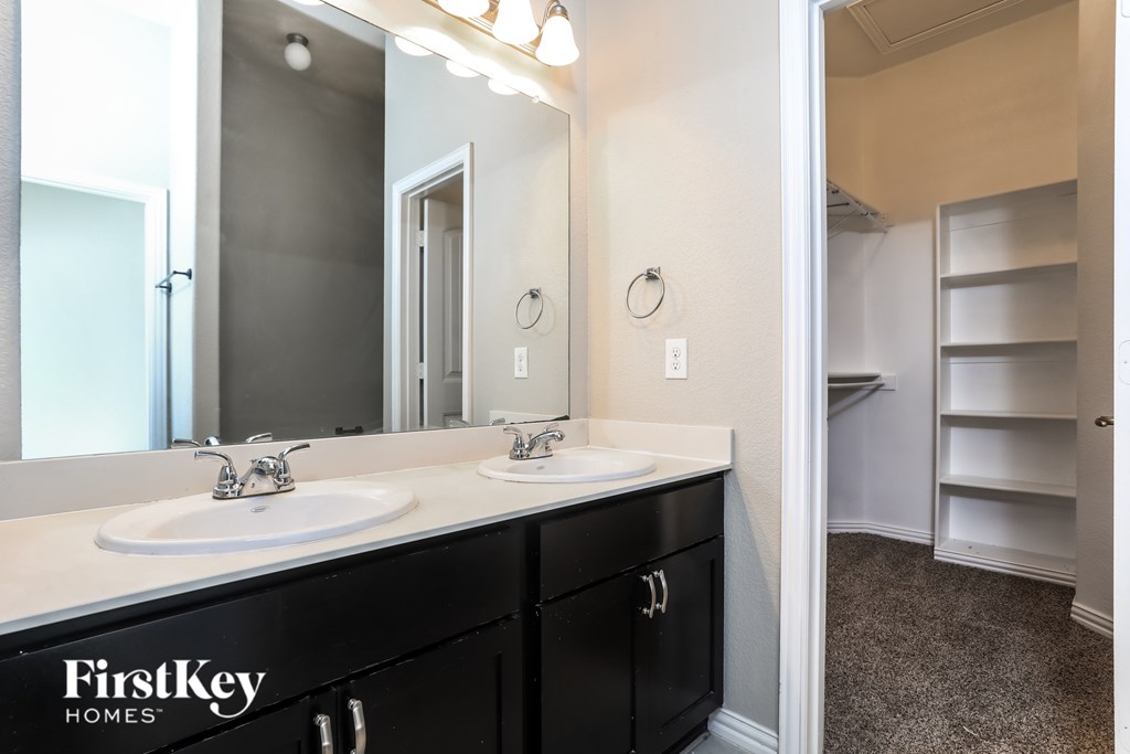 A bathroom with a double sink vanity and a mirror above it.
