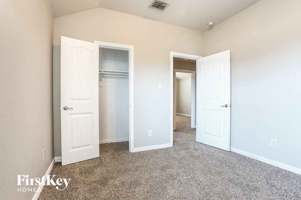 A room with a carpeted floor and two open doors.