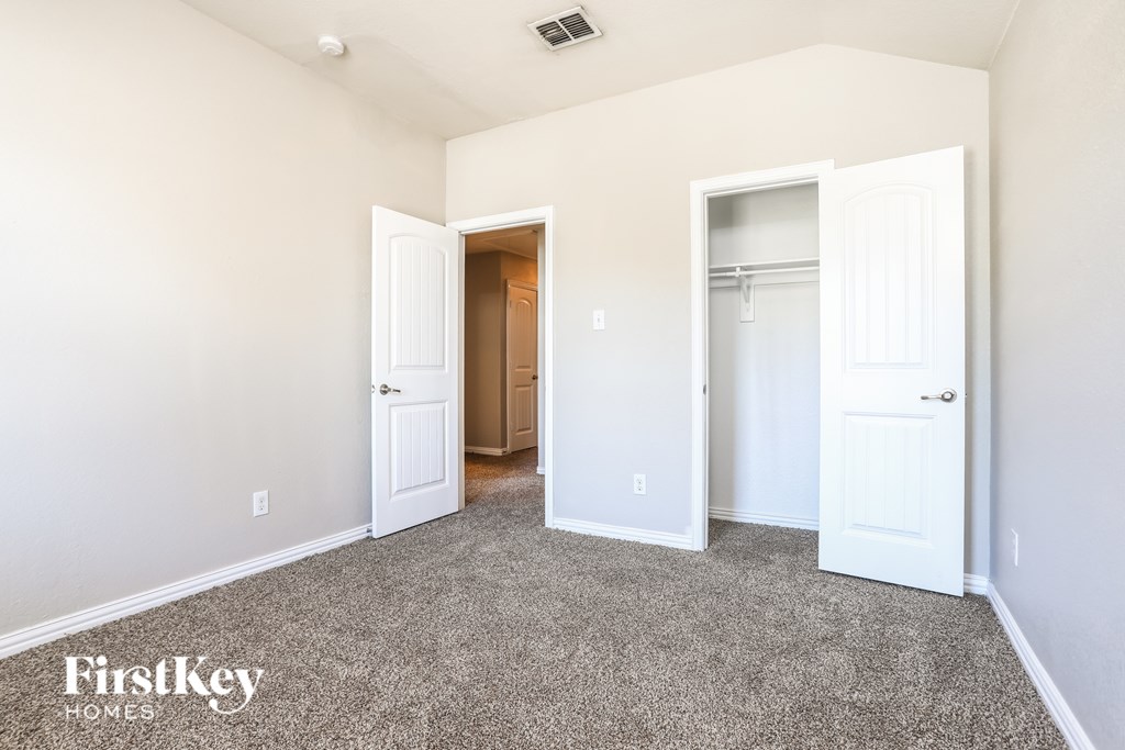A room with a carpeted floor and two white doors.