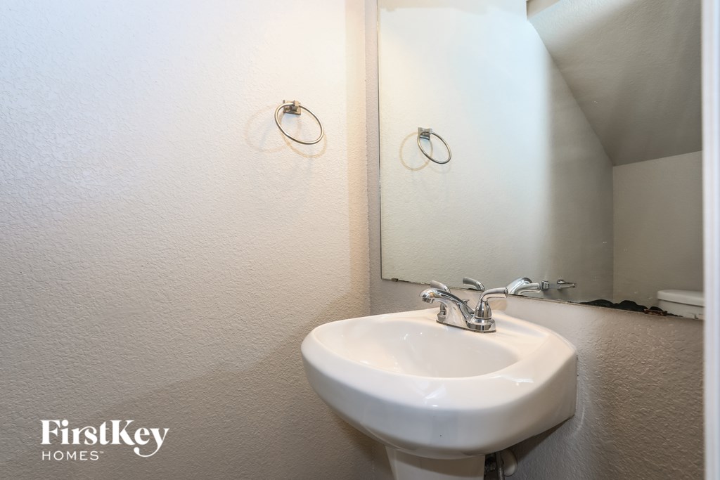 A white sink in a bathroom with a mirror and two rings on the wall.