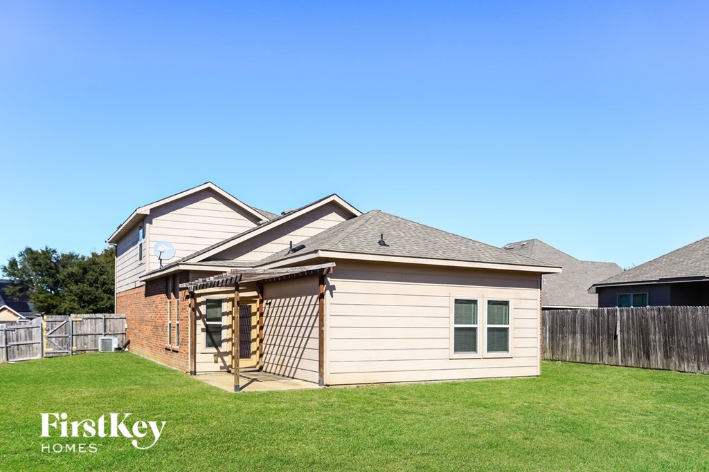A house with a fence and a tree in the background.