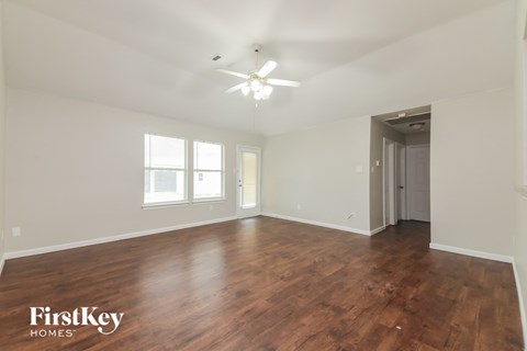 an empty living room with wood flooring and a ceiling fan
