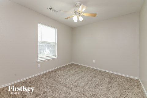 a bedroom with carpet and a ceiling fan and a window
