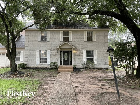 a white brick house with a black door and trees