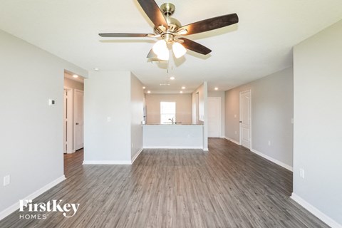 A spacious room with a ceiling fan and wooden flooring.