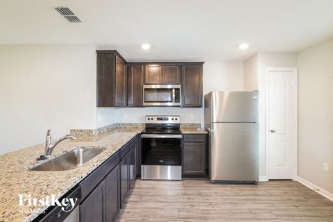 A kitchen with a sink, stove, and refrigerator.