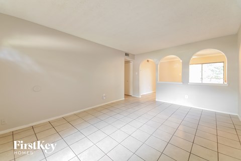 A spacious room with arched windows and tiled flooring.