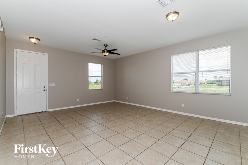 an empty living room with a ceiling fan and two windows