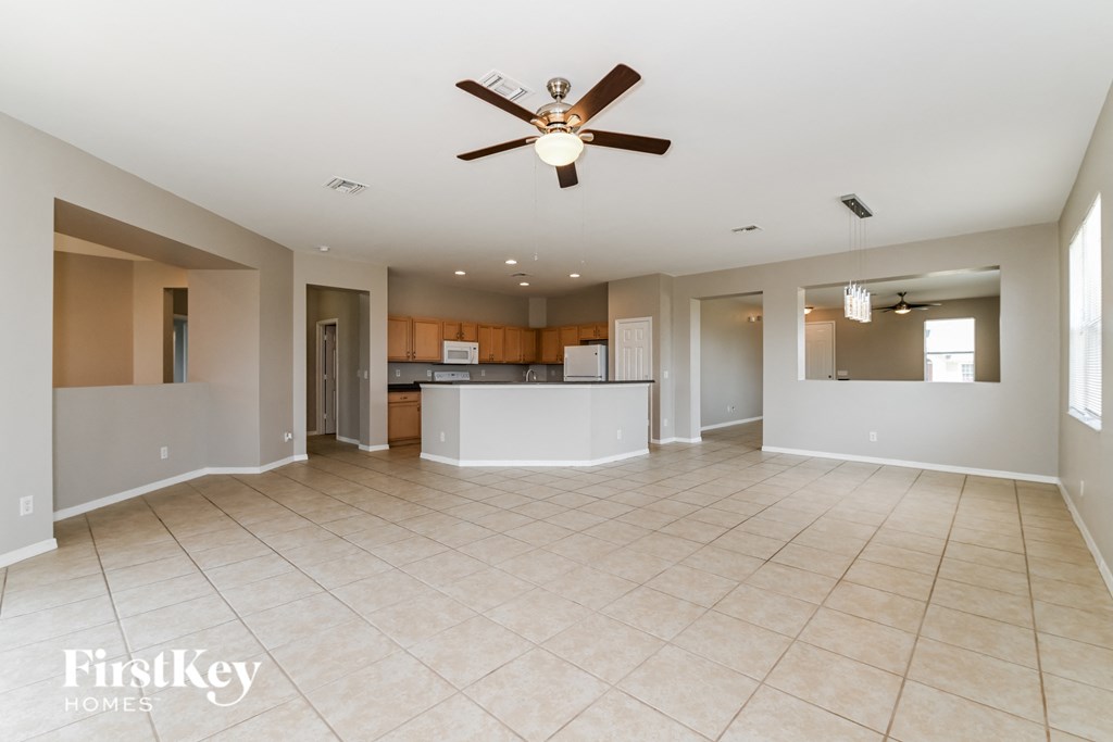 an empty living room and kitchen with a ceiling fan