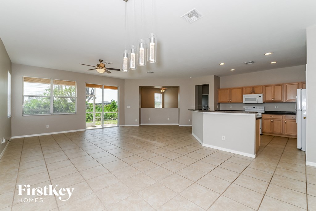 an open kitchen and living room with tile flooring and a ceiling fan