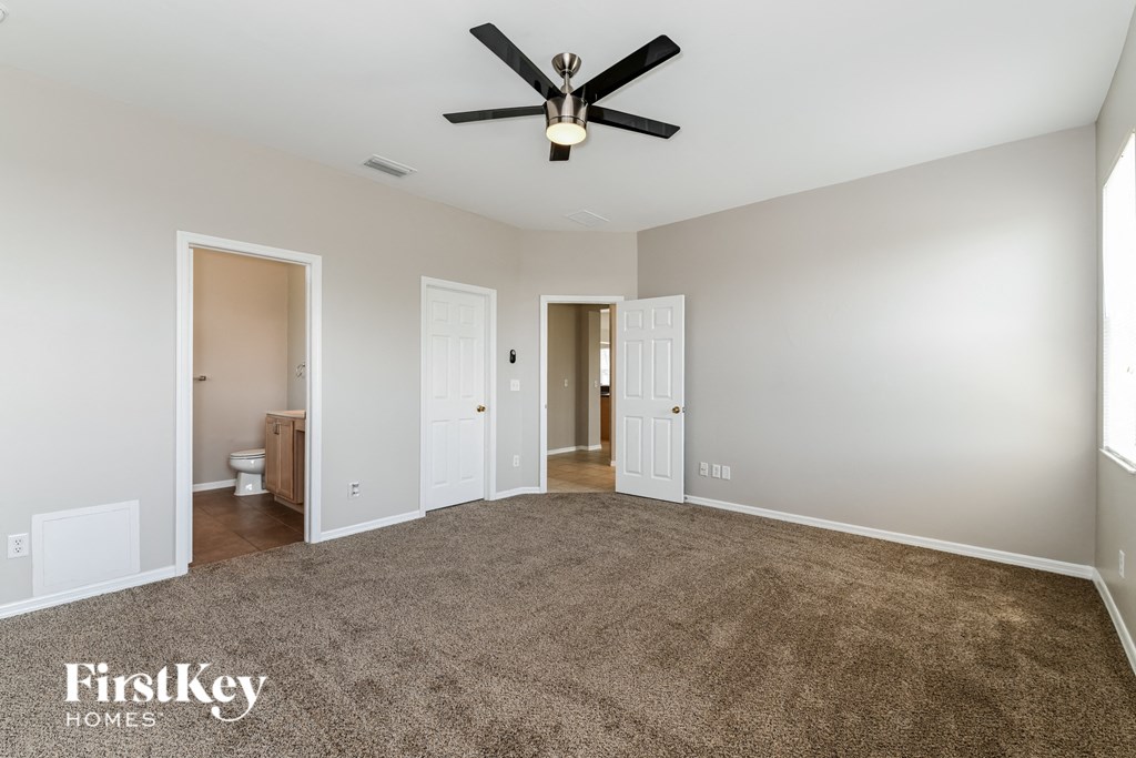 an empty living room with carpet and a ceiling fan