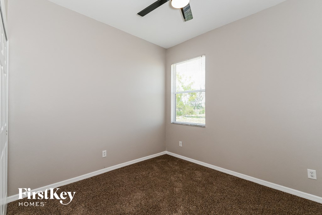 a bedroom with carpet and a window and a ceiling fan