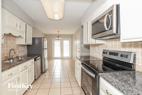 A kitchen with white cabinets and a black stove top oven.