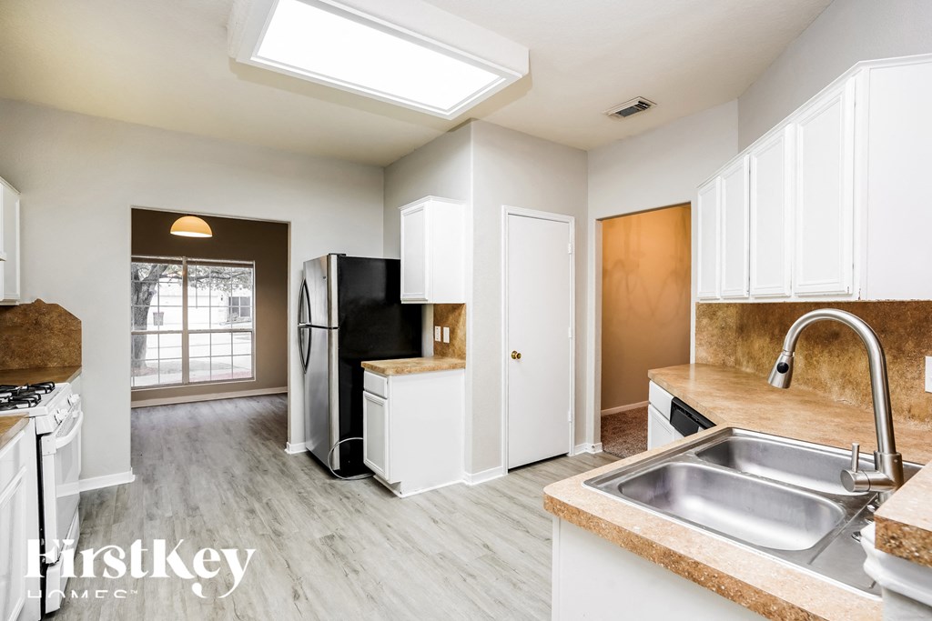 A kitchen with white cabinets and a stainless steel refrigerator.
