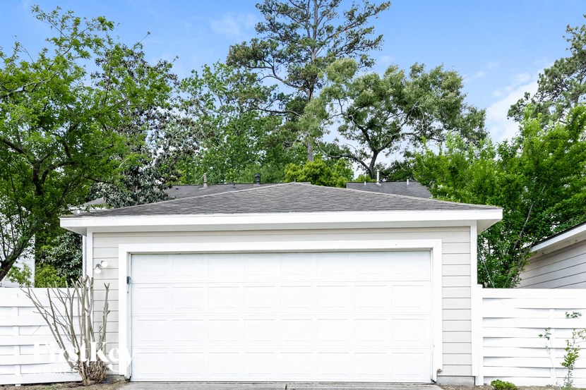 a white garage with a gray roof in front of trees