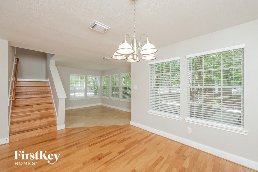 an empty living room with a hardwood floor and large windows