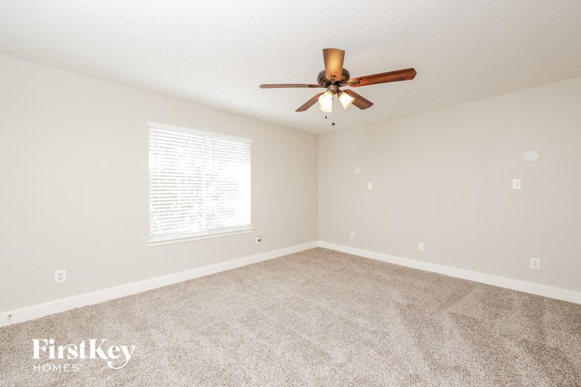 an empty living room with a ceiling fan and a window